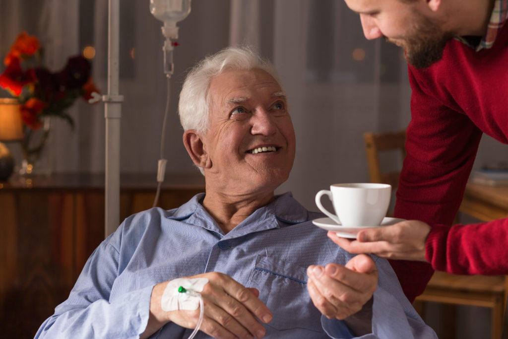 Male carer assisting incurable ill senior man