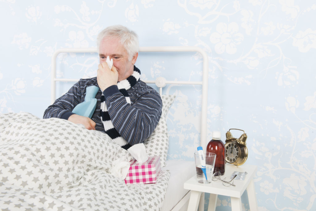 53874685 - senior man sick in bed with hot water bottle and thermometer